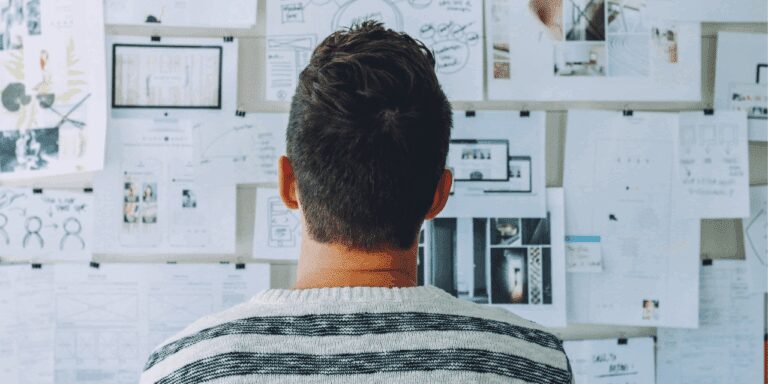 Person stands in front of a board full of ideas and documents